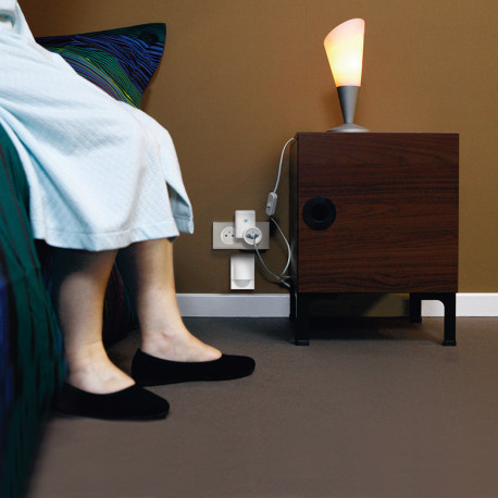 Personne dans une chambre à côté d'une prise électrique avec détecteur