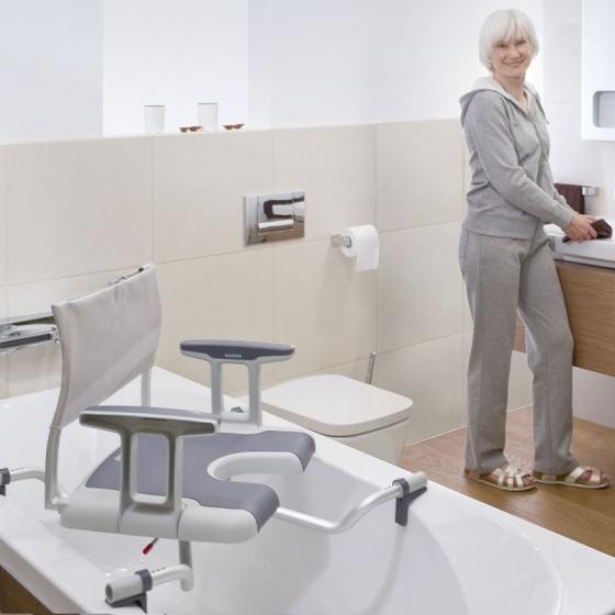 Personne dans une salle de bain regardant un siège de bain confort avec découpe intime