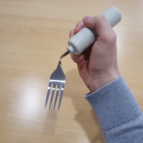 Couvert coudé avec manche grossi tenu dans une main