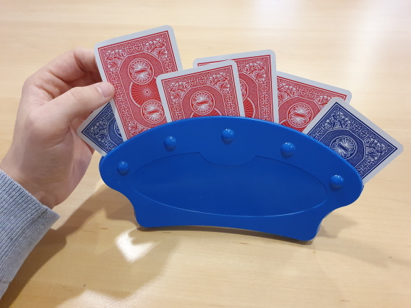 Main tirant une carte d'un support de cartes à jouer de couleur bleu