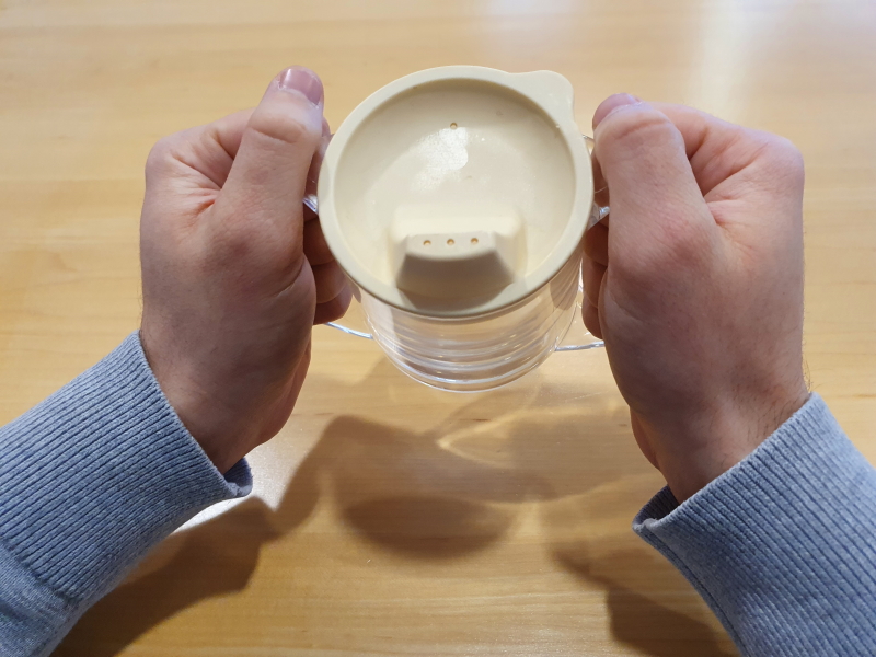 Verre avec anse et bec maintenu par deux mains