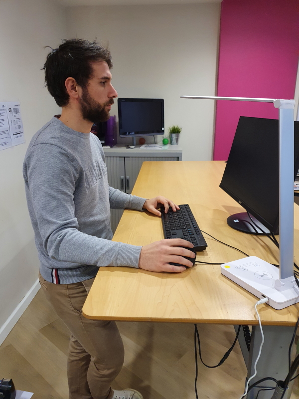 Personne debout devant un bureau à hauteur variable électriquement